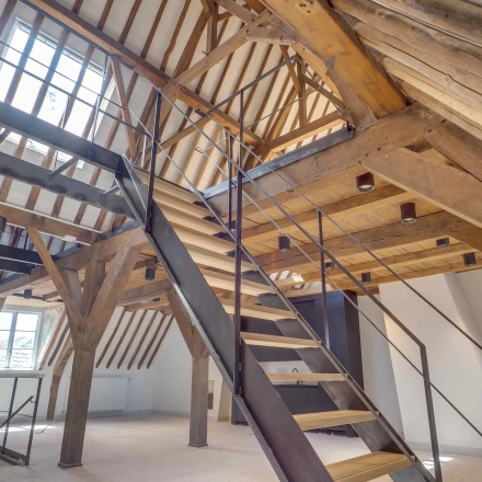 Spacious loft office space featuring exposed wooden beams, skylights, and a modern staircase at Brigittenstraat 22, ideal for rent office space in Utrecht Center.