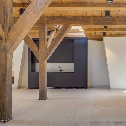 Spacious office space with rustic wooden beams and a small kitchenette area at Brigittenstraat 22, ideal for office space rental in Utrecht Center.