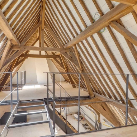 Interior view of an unfurnished attic office space with wooden beams at Brigittenstraat 22 in Utrecht Center. Ideal for office space rental opportunities.