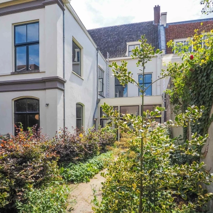 Exterior view of a charming office building at Brigittenstraat 22, Utrecht Center, ideal for office space rental with lush greenery.
