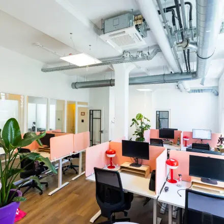 Bright office space with multiple workstations at Oudegracht 161, Utrecht Center, available for rent. The furnished interior includes large windows and modern decor, ideal for office space rental.