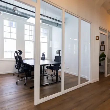 Modern office space at Oudegracht 161, Utrecht Center, featuring glass-walled meeting rooms with ergonomic chairs and wooden flooring, suitable for office space rental.