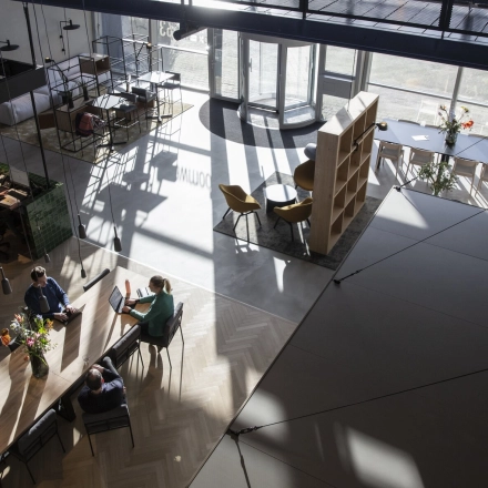 A modern, spacious office to rent at Atoomweg 63, Utrecht Lage Weide, featuring people collaborating at a large table in a naturally lit open floorplan.