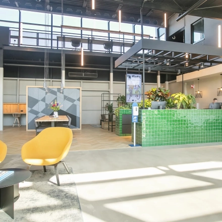 Bright office interior at Atoomweg 63, Utrecht Lage Weide, showcasing furnished open floorplan with inviting seating area and green reception desk, ideal for office space rental.