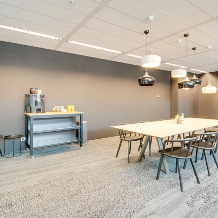 Modern office space rental at Computerweg 22, Utrecht Lage Weide, featuring a large meeting table and chairs, a beverage station, and a wall-mounted screen.