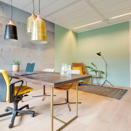 A bright and modern office space with stylish furnishings, located at Computerweg 22 in Utrecht Lage Weide, available for rent. Features a workspace with chairs, table, and plants.