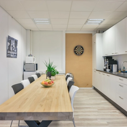 Bright, furnished office space at Kobaltweg 11 in Utrecht Lage Weide with a long table, chairs, and kitchen facilities available for rent.