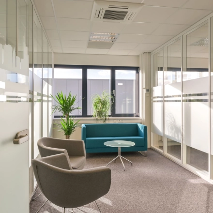 Bright office space with glass walls, a teal couch, and chairs available for rent at Kobaltweg 11, Utrecht Lage Weide.