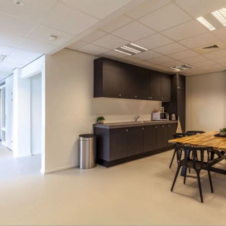 Modern Utrecht Lage Weide office space rental featuring a kitchenette and wooden dining table with chairs, offering a cozy workspace environment.
