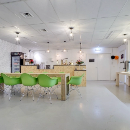 Modern office break area at Zonnebaan 18, Utrecht Lage Weide, with green chairs and a communal table. Ideal office space rental option.