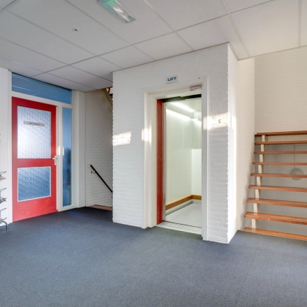Entrance area of an office building at Zonnebaan 18, Utrecht Lage Weide, featuring a staircase and elevator, ideal for office space rental.