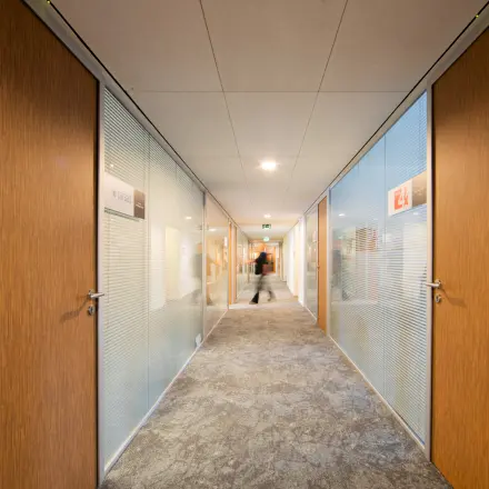 Modern hallway in an office at Middenburcht 136, Utrecht Leidsche Rijn, featuring glass doors and subtle lighting.