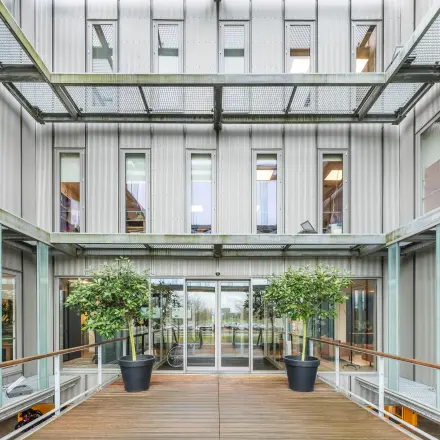 Exterior view of an office space for rent at Orteliuslaan 850, Utrecht Papendorp, showcasing a modern facade with large windows and a wooden walkway.