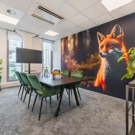 Bright office space for rent in Utrecht Papendorp featuring a large fox mural, conference table, chairs, and plants, offering a modern setup for meetings.