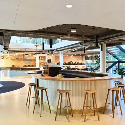 Modern open floor plan with a circular bar, stools, and natural light at Van Deventerlaan 30-40 in Utrecht Papendorp for office space rental.