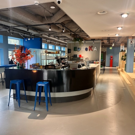 Modern office lounge at Daltonlaan 200, Utrecht Rijnsweerd with a sleek bar area, vibrant decor, and stools. Ideal for office space rental.