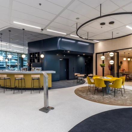 Bright, modern office space in Utrecht South, featuring a stylish lounge area with yellow chairs, round tables, and contemporary lighting. Ideal for office space rental opportunities.