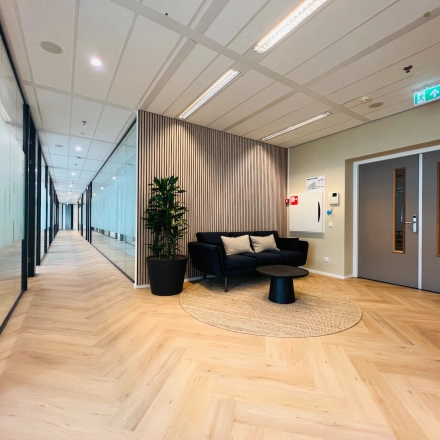 Modern office space in Utrecht South, ideal for rent, featuring a furnished corridor with cozy seating and stylish decor.