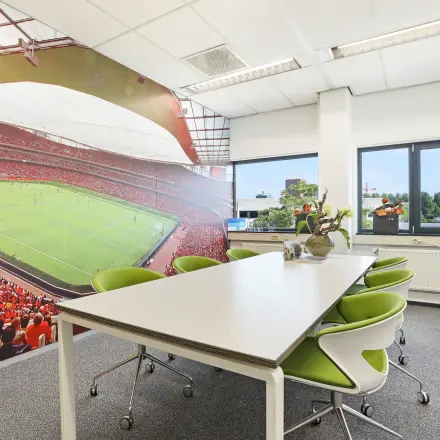 Bright office space at Winthontlaan 200, Utrecht South, featuring modern furnishings and a vibrant stadium mural, perfect for rental.