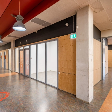Contemporary interior hallway at Proostwetering 41, Utrecht West, suitable for office space rental. Features a modern design with glass-walled rooms and decorative flooring, offering a professional vibe for business activities.
