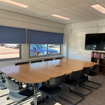 Bright office space for rent at Zonnebaan 54 in Utrecht West, featuring a large conference table, wall-mounted TV, and bookshelf. Ideal for office space rental and meetings.