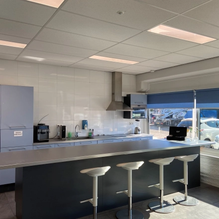 Bright office pantry with bar stools and a window view, suitable for office space rental in Utrecht West.