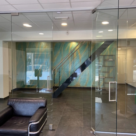 Modern office entrance with glass walls and a black leather chair at Zonnebaan 54, ideal for those seeking office space rental in Utrecht West.