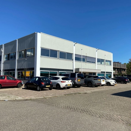 Exterior view of an office building at Zonnebaan 54, Utrecht West, suitable for office space rental. Several cars are parked outside the office to rent.