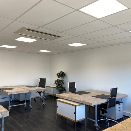 Bright office space with wooden desks and black office chairs at Zonnebaan 54, Utrecht West, ideal for those looking to rent office space. Modern lighting enhances the open, welcoming environment.