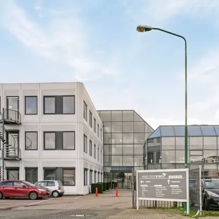 Exterior view of the office building located at De Run 4312, Veldhoven, showcasing a modern facade with ample parking space, ideal for office space rental.