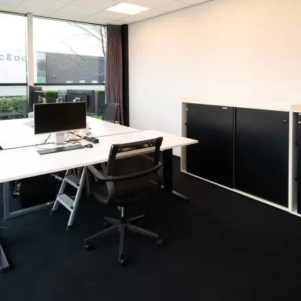 Modern office space at Gildestraat 13 in Velp with sleek desks, chairs, and a window view, ideal for rental.
