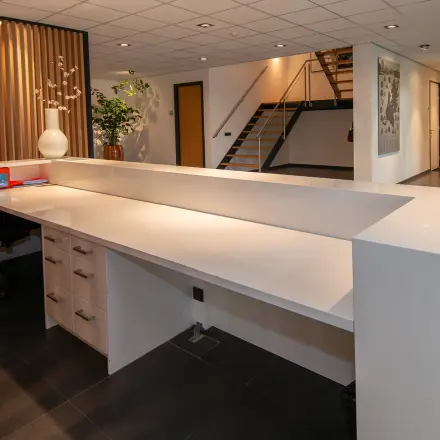 Modern reception area in an office to rent at Gildestraat 13, Velp, featuring a spacious desk with storage and contemporary design elements.