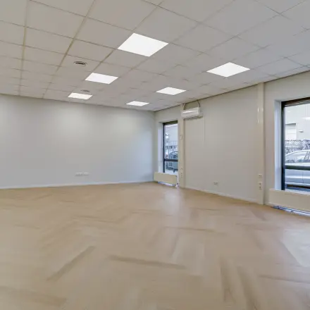 Open floorplan office space to rent at Keizersveld 47, Venray, featuring large windows with ample natural light and a neutral interior design ideal for customization.