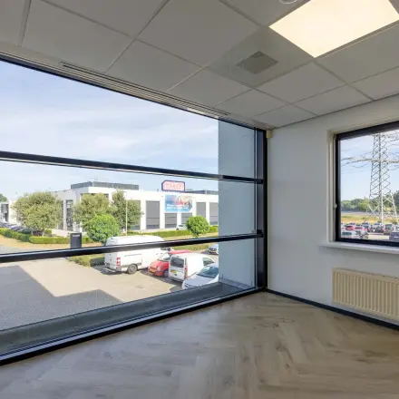 Unfurnished office space with large windows at Keizersveld 47, Venray, ideal for rent. Bright area with view of parking and neighboring buildings.
