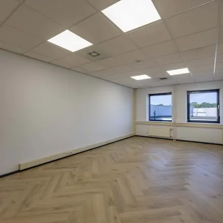 Spacious unfurnished office space with parquet flooring and large windows at Keizersveld 47 in Venray, ideal for office space rental.