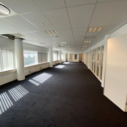 Spacious office interior at Regulusweg 11, Voorburg, featuring broad windows and neutral walls, perfect for an open-floor plan layout. Ideal for businesses seeking office space rental in a well-lit environment.