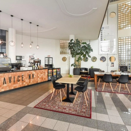 A furnished office space at Regulusweg 11, Voorburg, featuring a stylish coffee area with tables and chairs, ideal for office space rental.