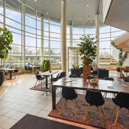 Spacious, modern office interior with large windows and tables, ideal for office space rental at Regulusweg 11, Voorburg.