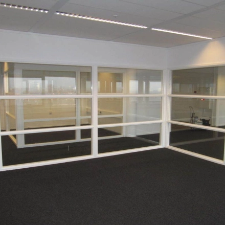 Interior view of office space at Regulusweg 11, Voorburg, featuring glass partitions and carpeted floors, ideal for those looking for office space rental.