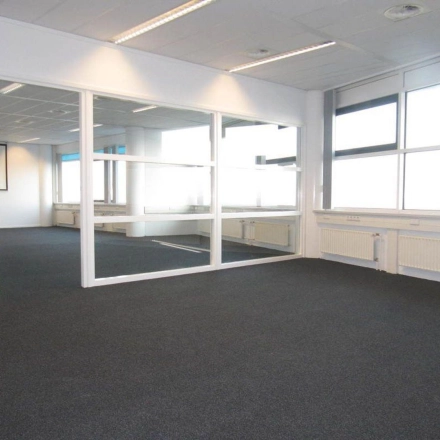 Bright, unfurnished office space available for rent at Regulusweg 11, Voorburg, featuring large windows and a glass partition for versatile office space rental options.