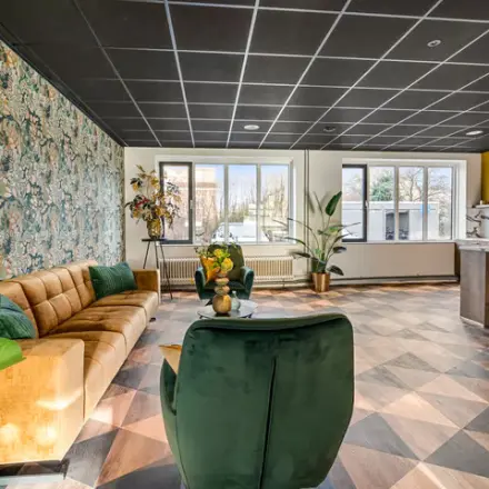 Spacious, well-lit furnished office to rent at Agro Business Park 22, Wageningen, featuring stylish seating and vibrant decor for a comfortable workspace atmosphere.