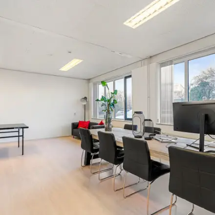 Bright office space for rent at Agro Business Park 22 in Wageningen, featuring a long wooden desk, modern chairs, and large windows providing natural light.
