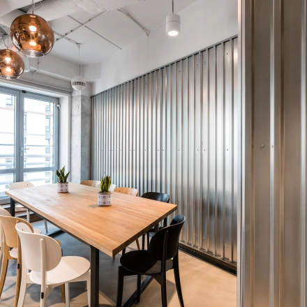 Modern conference room with a wooden table, monochrome chairs, and stylish lighting at Konstruktorska 11, a prime office space rental location in Warsaw Mokotow.