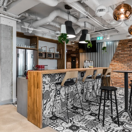 Modern office space located at Konstruktorska 11 in Warsaw Mokotow features a stylish lounge area with a bar, high stools, and contemporary decor, ideal for office space rental.