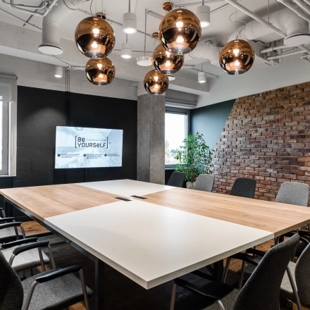 Modern conference room at Konstruktorska 11, Warsaw Mokotow, available for office space rental, featuring a large table, chairs, and stylish lighting.