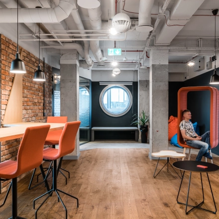 Modern office space at Konstruktorska 11, Warsaw Mokotow featuring stylish seating and a person engaged in business activities.