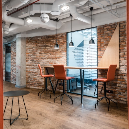 Stylish office space with brick walls, modern pendant lighting, and high-top seating at Konstruktorska 11, ideal for rent office space in Warsaw Mokotow.