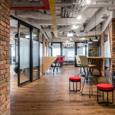 A furnished office space in Warsaw Mokotow at Konstruktorska 11, featuring stylish seating areas and brick accents, perfect for office space rental.