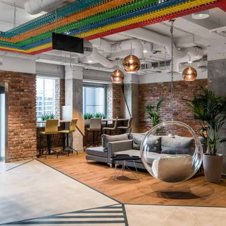 Modern office space for rent in Warsaw Mokotow, featuring stylish decor, cozy seating areas, and plants enhancing a welcoming atmosphere.