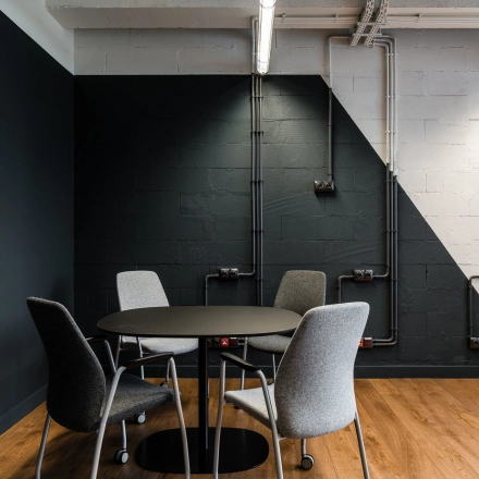 Office space rental at Konstruktorska 11, Warsaw Mokotow featuring a stylish round table and modern chairs in an industrial setting.